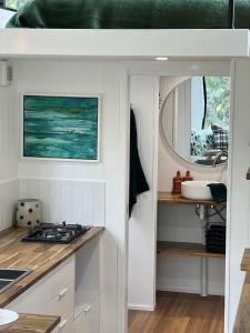 AlonnahLittle Pardalote Tiny Home Bruny Island的厨房配有白色橱柜、水槽和镜子