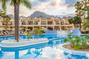 阿德耶皇家日落海滩俱乐部钻石度假公寓的一个带棕榈树游泳池和一座建筑的度假村