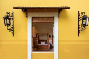 梅里达Hacienda Xcanatun, Angsana Heritage Collection的黄色的墙壁,上面有窗户和灯