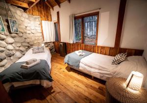 拉安戈斯图拉镇Ruma Andina by DOT Cabana的一间卧室设有两张床和石墙