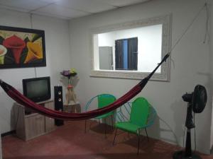 圣玛尔塔Casa CamiMar, Casa Amoblada solo para tí y tú familia的一个带椅子和电视的房间的吊床