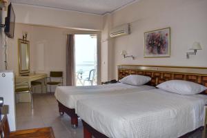 迈索隆吉翁Hotel Theoxenia的一间卧室配有两张床、一张桌子和一张书桌