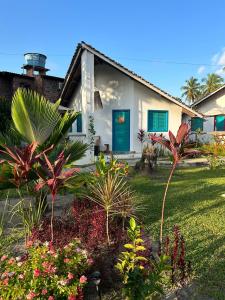 塔曼达雷Chalés Jardins dos Cajueiros的白色的房子,有蓝色的门和一些植物