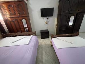 阿斯旺Bakar house的一间卧室设有两张床,墙上配有电视。