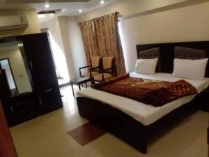 伊斯兰堡PAK HOTEL Islamabad的一间卧室配有一张大床和一把椅子