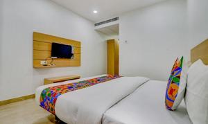 瓦拉纳西FabHotel Premium Kashi的卧室配有一张白色大床和电视。