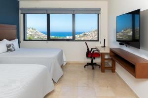 圣何塞德尔卡沃Gamma Los Cabos的一间卧室配有两张床、一张桌子和一台电视。