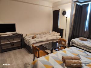 莱斯特St Lucia lodge Leicester long stays available的客房设有两张床和一张桌子及一台电视