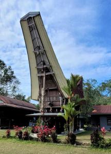 兰特包Toraja Homestay & Coffee Bunna的前方有花朵的三角形屋顶建筑