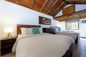 格兰德海滩瑞普杰克酒店的卧室设有2张床和木制天花板。