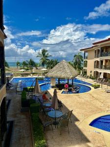 雅科Apartamento de lujo frente a playa Jacó-3 BD/ 2 BA的毗邻度假酒店的带椅子和遮阳伞的游泳池