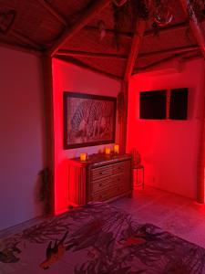 勒博塞Mas des rochers - Case bambou的一间红色灯光的卧室和一张带梳妆台的床