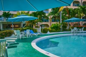 基督教堂市太阳湾酒店的一个带蓝伞、椅子和桌子的游泳池