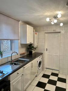 伦敦Holiday Home in Walthamstow的厨房配有白色橱柜和黑白格子地板。