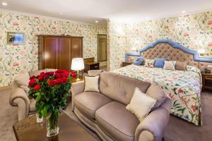 利沃夫瑞士酒店 的一间卧室配有一张床、一张沙发和玫瑰花