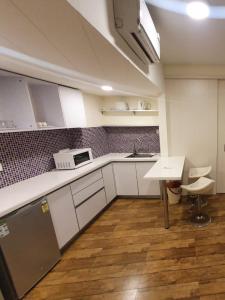 苏拉特Rajhans Belliza , Hotel apartment units的厨房配有白色橱柜、桌子和水槽。