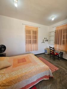 卡兰卡斯Chalé Arcos do Sol - Carrancas的一间卧室配有一张床和一把椅子