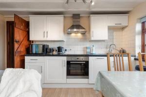 桑德斯富特Cowslip Cottage Serenity with Jacuzzi的厨房配有白色橱柜和炉灶烤箱。