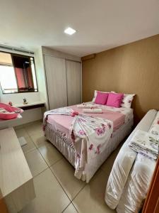 卡贝德卢Apartamento a beira mar com piscina estilo resort的一间卧室配有两张带粉色和白色床单的床