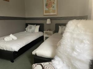赫克瑟姆The Sun Inn的一间卧室配有两张带白色床单和灯的床