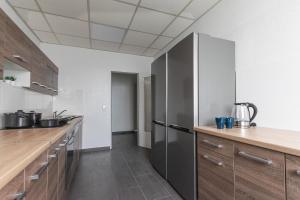 诺伊斯T&K Apartments 6 and 10 Room Apartment in Neuss for big Groups 22min to Fair DUS的厨房配有不锈钢冰箱和木制橱柜