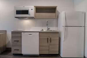 斯特灵海茨WoodSpring Suites Detroit Sterling Heights的厨房配有白色冰箱和微波炉