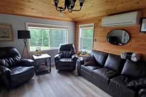 安蒂戈尼什Lochaber Lakeview Cottage的客厅配有真皮沙发和两把椅子