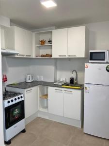 梅塞德斯Apartamento céntrico en Mercedes Uruguay的厨房配有白色橱柜、炉灶和冰箱。