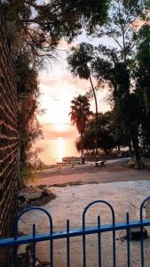 提比里亚בית על חוף כנרת的海滩前的蓝色长椅,享有日落美景