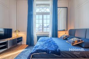 里摩日The Little Cérez Luminous Studio in the Heart of Limoges的一间卧室配有一张带蓝色窗帘的床和电视。