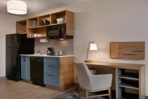 堪萨斯城堪萨斯城东北烛木套房酒店的一间带书桌和黑冰箱的小厨房