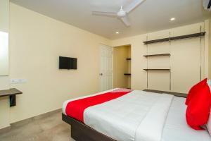 班加罗尔Super OYO Flagship Olivia Comforts Near Nexus Mall Koramangala的一间卧室设有红色和白色的床和一台电视。