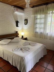 托雷斯Pousada House Sol & Praia的一间卧室配有一张带白色床单的床和一扇窗户。