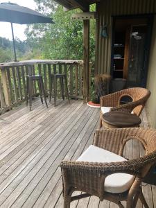 TawharanuiKākā Ridge Retreat Bush Hideaway的一个带桌椅和遮阳伞的甲板