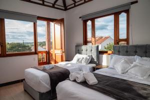 莱瓦镇HOTEL ALTIPLANO VILLA DE LEYVA的带大窗户的客房内的两张床