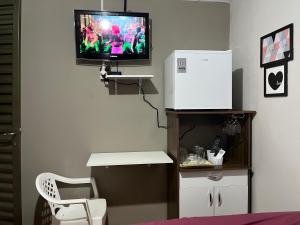 里奥韦尔迪Casa Recanto - Quarto simples的配有电视和白色椅子的房间