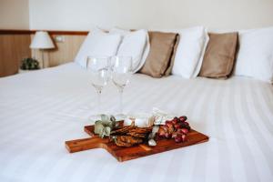 沃加沃加阿斯特酒店的床上的食品托盘和两杯酒杯