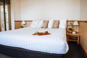 沃加沃加阿斯特酒店的一张大白色的床,上面有酒杯托盘