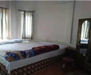 拉塔古里Akarshan Bono Bunglow的一间卧室设有一张大床和两个窗户