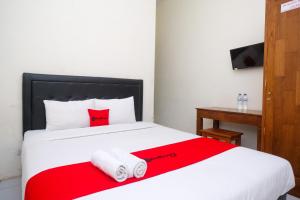 科贾扬RedDoorz Syariah at Griya Hanum Condoongcatur的卧室配有红色和白色的床和毛巾