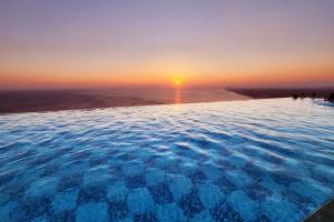 江陵市Gangneung Chonpines Ocean Suites Hotel的一座享有日落美景的无边游泳池