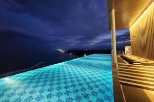 江陵市Gangneung Chonpines Ocean Suites Hotel的游泳池,晚上可欣赏到水景