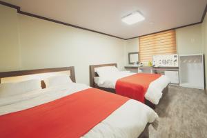 顺天市Hotel Castle的一间卧室配有两张红色和白色床单