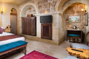 奥塔希萨尔Cappadocia Pema Cave Hotel的一间卧室设有一张床,并在石墙内配有电视。