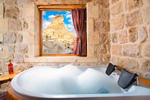 奥塔希萨尔Cappadocia Pema Cave Hotel的带浴缸的石质浴室设有窗户。