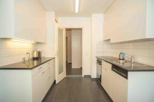 巴塞尔Modern 3-bedroom apartment in city centre的厨房配有白色橱柜和黑色台面
