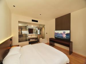 丽江夕露星期六智能度假花苑的卧室配有白色的床和平面电视。