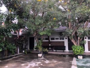 帕卢RedDooz Plus At Ininnawa Homestay Syariah Palu的庭院里种有树木和长凳的房子