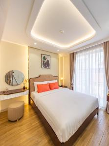 胡志明市Simmi Apartment Phu My Hung的一间卧室配有一张带橙色枕头的大床
