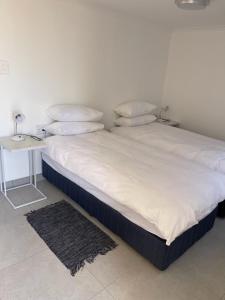 吕德里茨The Oasis Accommodation的一张带白色床单和枕头的床以及一张桌子